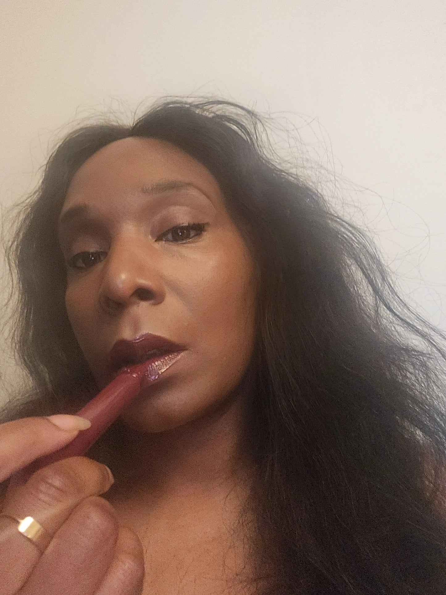 Person applying lipstick with a brush on a neutral background